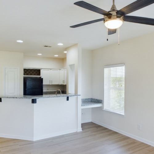 living room photo with ceiling fan and kitchen bar space