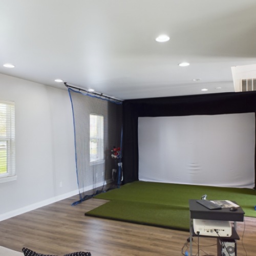 golf simulator with couch and tables